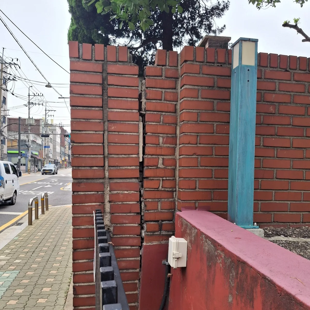 적벽돌 담장 두 부분의 연결부가 위에서 아래까지 벌어진 상태