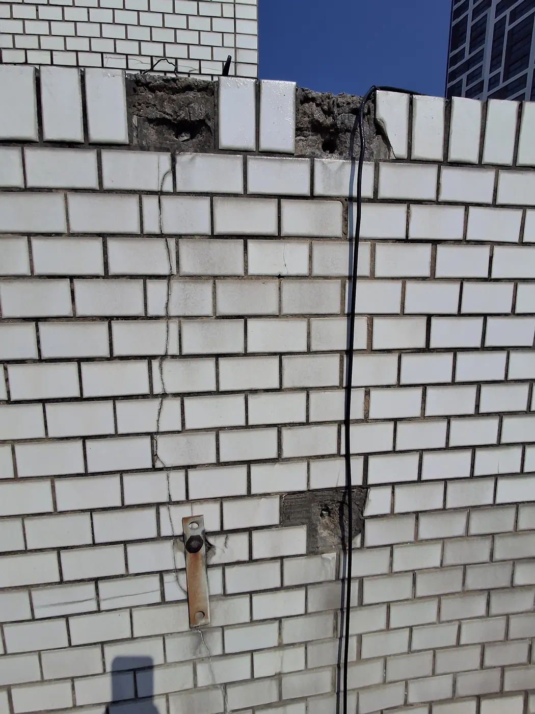 부천 외벽크랙보수 시공 전 타일 외벽 상단의 시멘트가 떨어지고 배선 주변이 드러난 상태